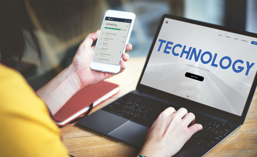 Woman on laptop and holding mobile phone