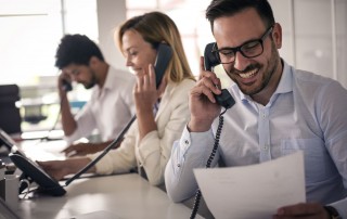 three office workers talking on deskphones