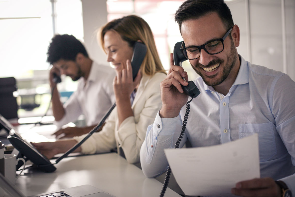 three office workers talking on deskphones
