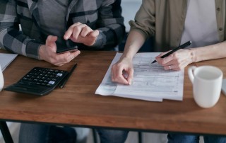 Man and woman at desk with paperwork and calculator