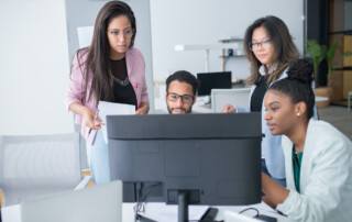 Work colleagues gathered around a computer