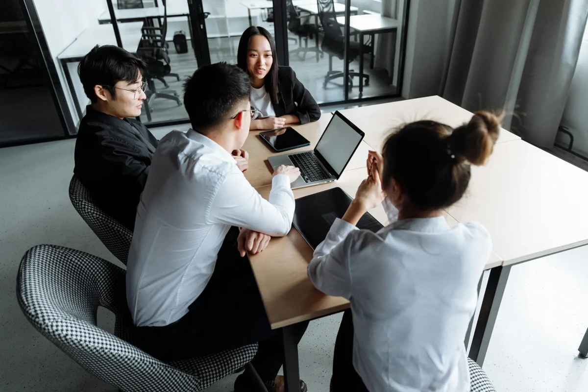 Colleagues sat around a table talking with laptops and tablet device