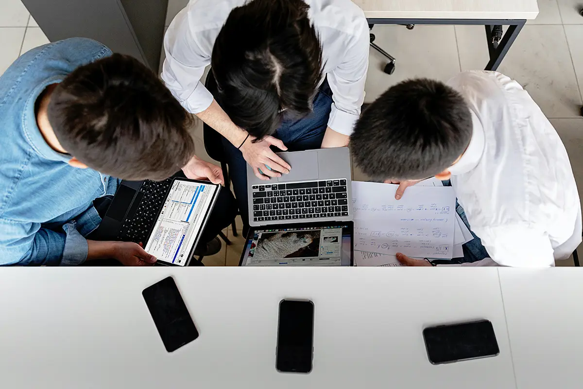 group of colleagues gathered around laptop
