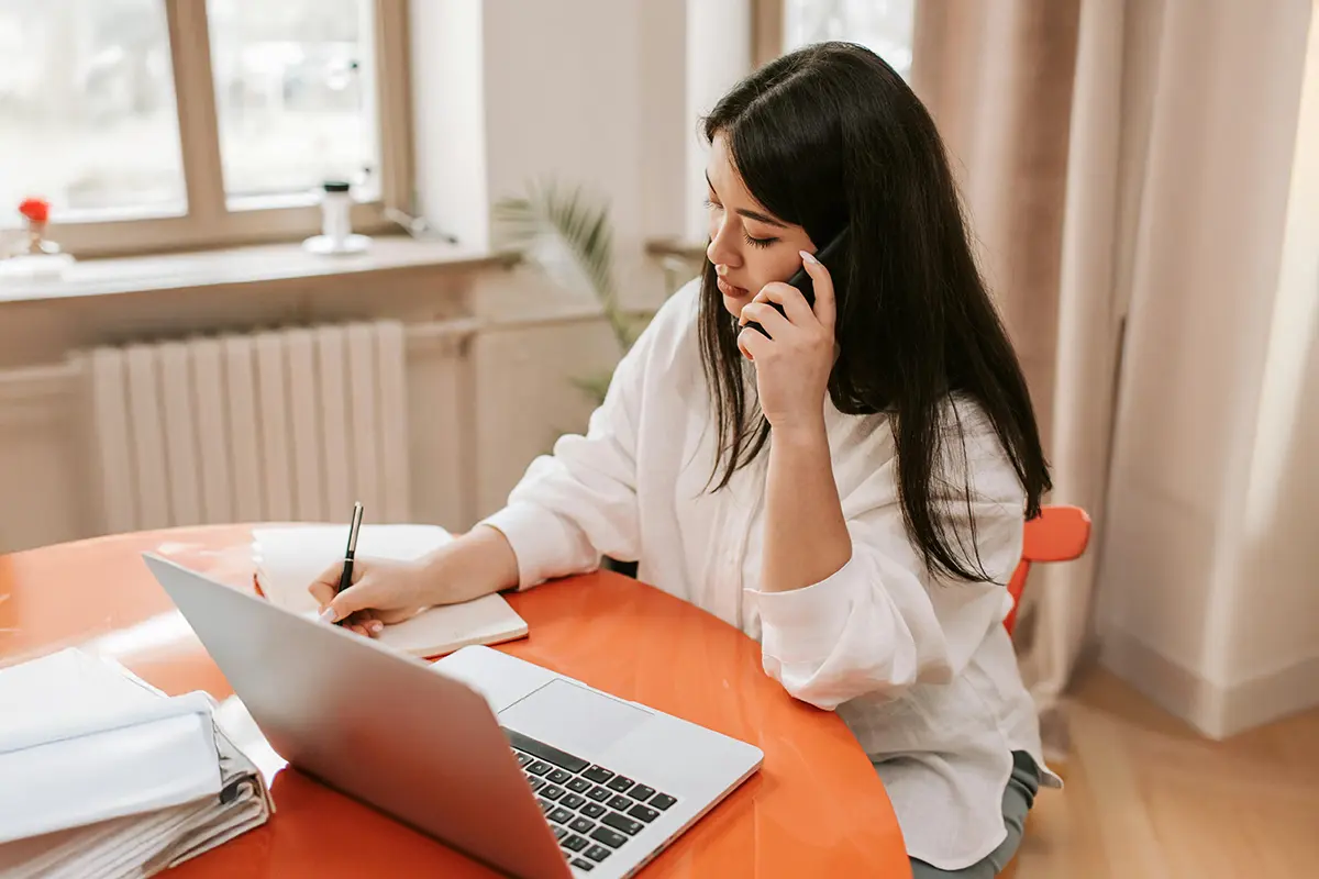 Woman sat behind laptop and speaking on mobile