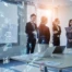 Group of professionals in a modern office discussing business strategy, with digital graphics overlay showing cloud computing, analytics icons, and financial data points.