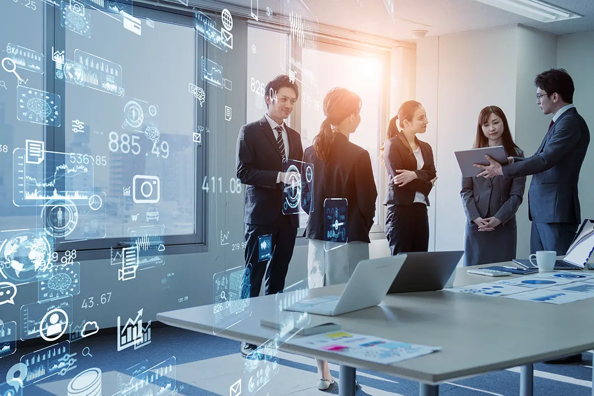 Group of professionals in a modern office discussing business strategy, with digital graphics overlay showing cloud computing, analytics icons, and financial data points.